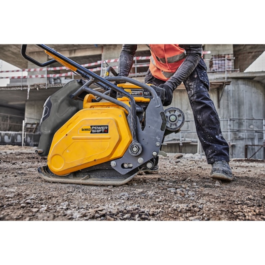 DEWALT Power Shift plate compactor in use at a construction site, operated by a worker in safety gear.