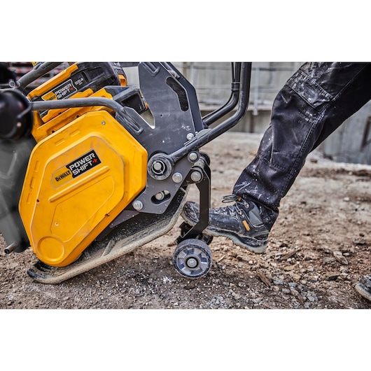 DEWALT Power Shift compactor being operated on a rough outdoor surface by a person in work boots.