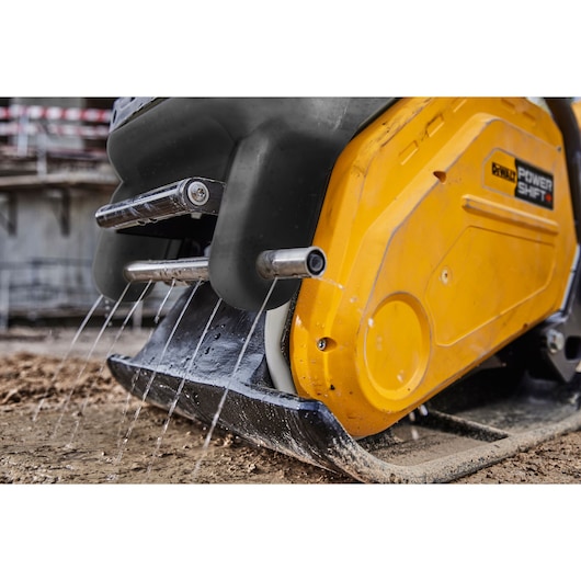 Close-up of a DEWALT Power Shift machine with water jets spraying onto a muddy ground.