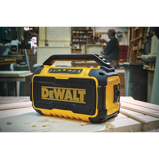 DEWALT portable Bluetooth speaker on a workbench in a workshop setting.