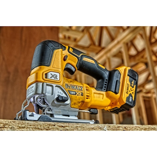 DEWALT DCS334P2 cordless jigsaw tool on a wooden surface, used for precise cutting in construction settings.