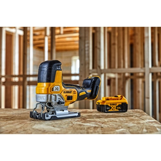 DEWALT cordless jigsaw with battery on a wooden surface in a construction setting.