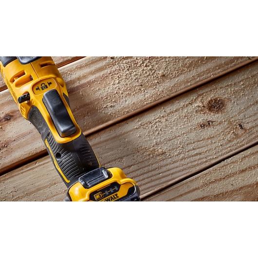 DEWALT power tool on wooden boards with sawdust, showing handle and controls.