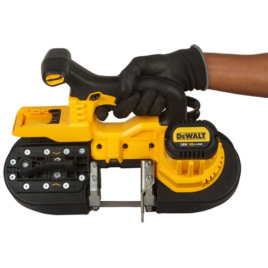 A gloved hand holding a DEWALT 18V XR Li-Ion portable band saw. The tool has a yellow and black design and is shown from the side.