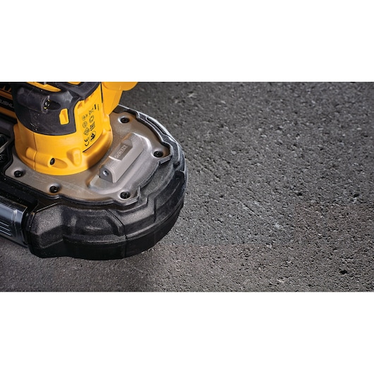 Close-up of the DEWALT DCS377NT power tool resting on a rough concrete surface.