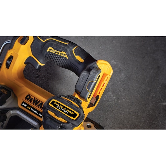 Close-up of a DEWALT brushless motor power tool handle, showing yellow and black details on a dark surface.