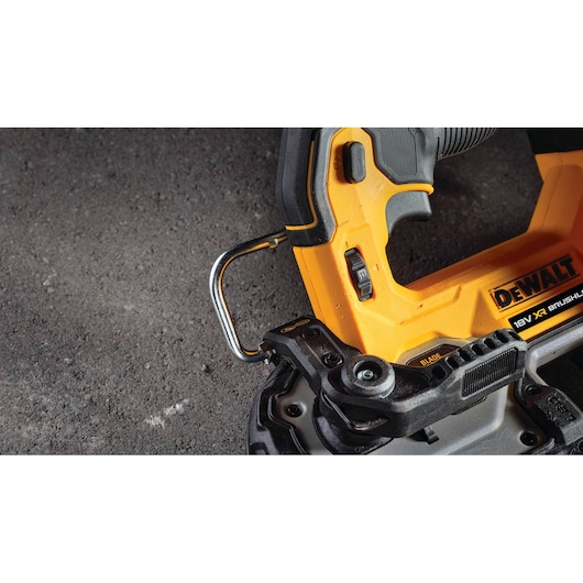 Close-up of DEWALT 18V brushless power tool handle and metal hook on a textured surface.