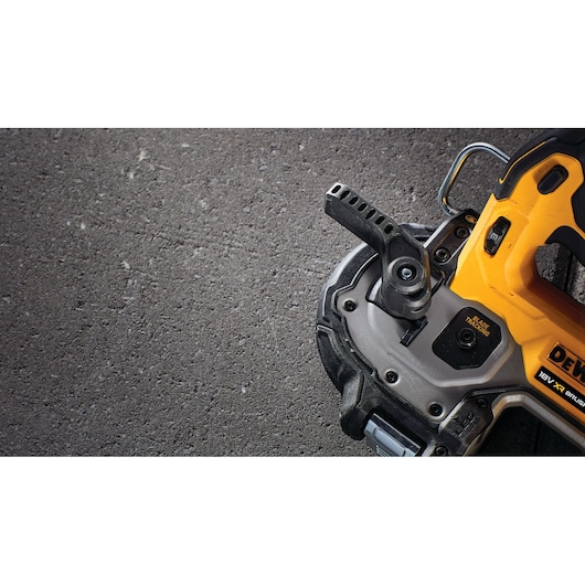 Close-up of a DEWALT power tool, yellow and black, on a textured surface, showing part of handle and base.