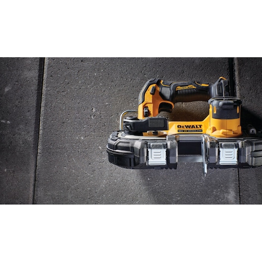 DEWALT cordless handheld bandsaw tool on a stone surface, shown from above.