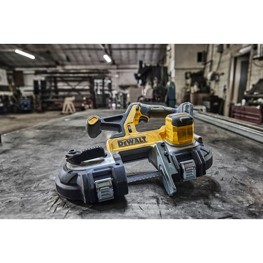 DEWALT cordless band saw placed on a metal workbench in a workshop setting.