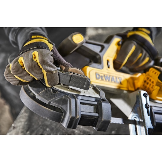 Gloved hands adjust a DEWALT power tool, focusing on a close-up of the handle and blade area.