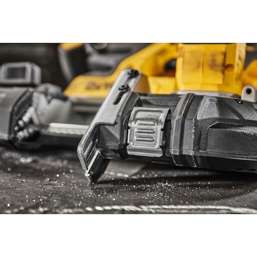 Close-up of a DEWALT power tool, showing the blade and part of the yellow handle with dust on the surface.