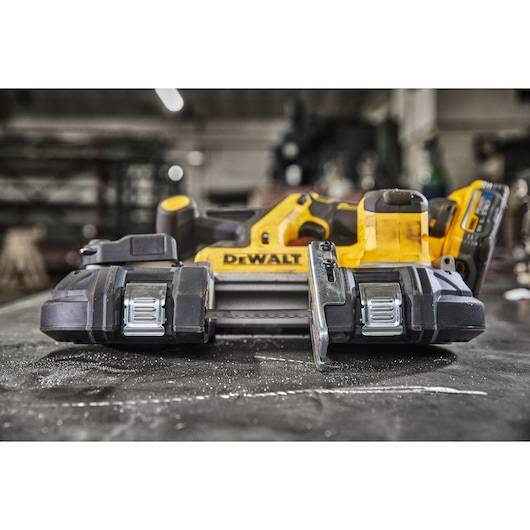 DEWALT cordless band saw placed on a workbench in an industrial workshop setting.