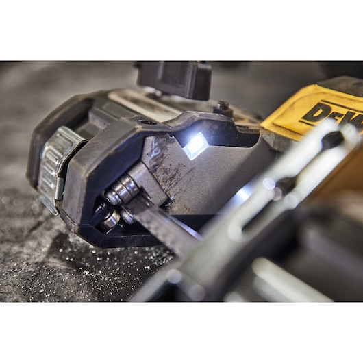 Close-up of a DEWALT band saw in use, with LED light and visible metal cutting.