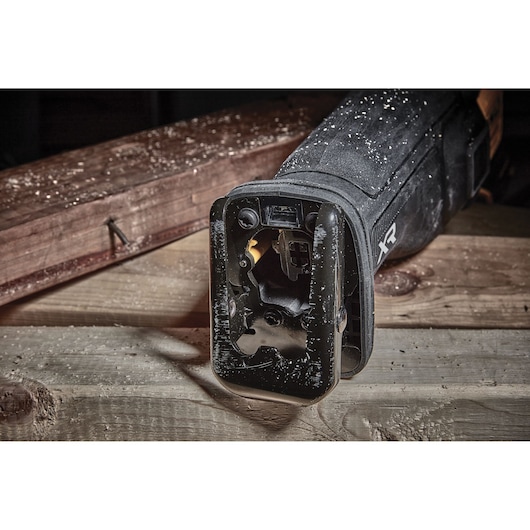 Close-up of a DEWALT reciprocating saw resting on wooden planks with sawdust visible.