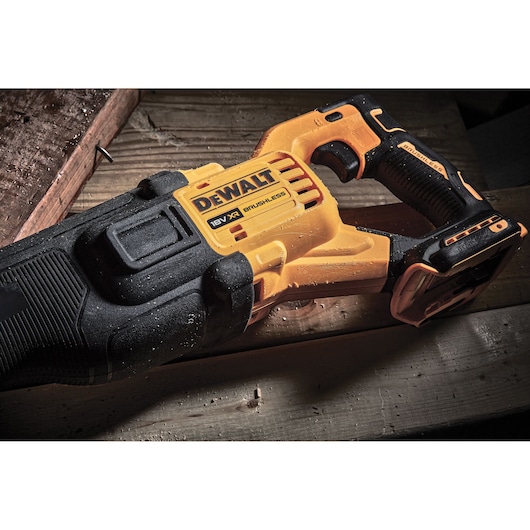 DEWALT 18V XR brushless reciprocating saw placed on a wooden surface, showing tool details and rugged design.