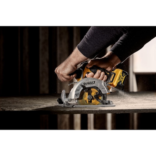 DEWALT circular saw in use, DCS512P2-QW and DCS512P2 SKUs, shown cutting wood in a workshop.
