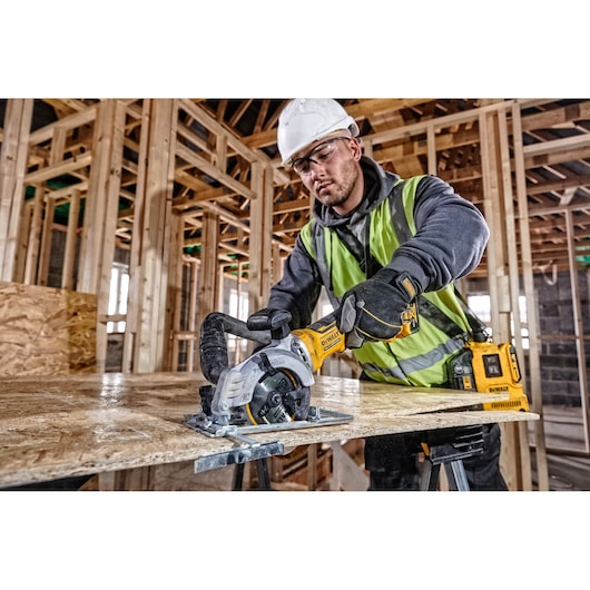 DEWALT DCS571NT-XJ, DCS571NT saw in use at construction site. Worker wears safety gear. Photography category.