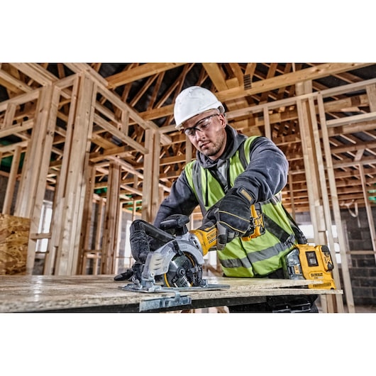 DEWALT DCS571NT-XJ and DCS571NT saw used by worker for wood cutting at construction site. Photography category.