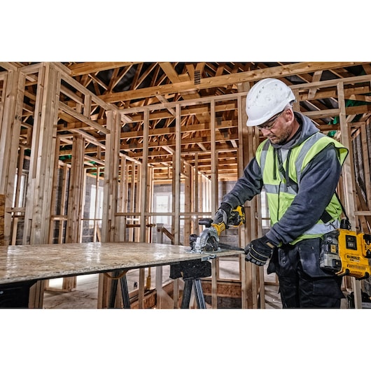 DEWALT DCS571NT-XJ, DCS571NT saw used on wood at construction site, worker in safety gear.