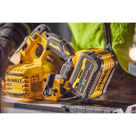Close-up of a DEWALT cordless circular saw with attached XR FLEXVOLT battery on a workbench.