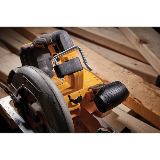 Close-up of DEWALT circular saw DCS573NT on wooden planks, showing handle and blade guard.