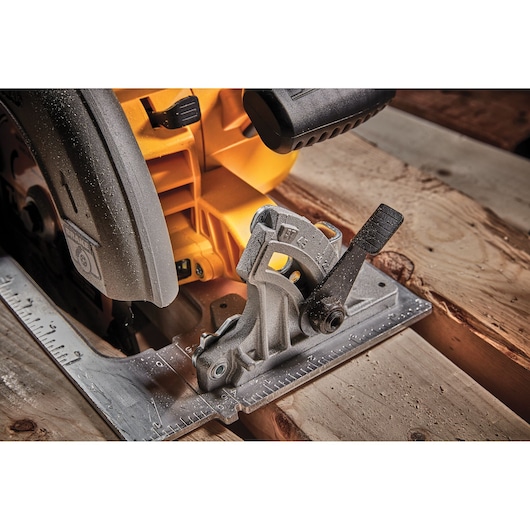 Close-up of a DEWALT circular saw adjusting angle on wooden planks.