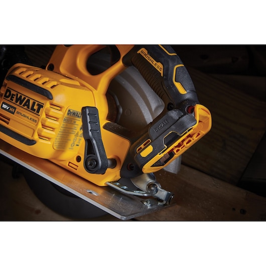 Close-up of a DEWALT 18V XR brushless circular saw cutting wood, showing handle and motor details.