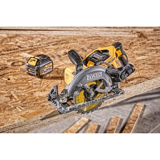 Dewalt cordless circular saw and battery on a plywood sheet in a workshop setting.
