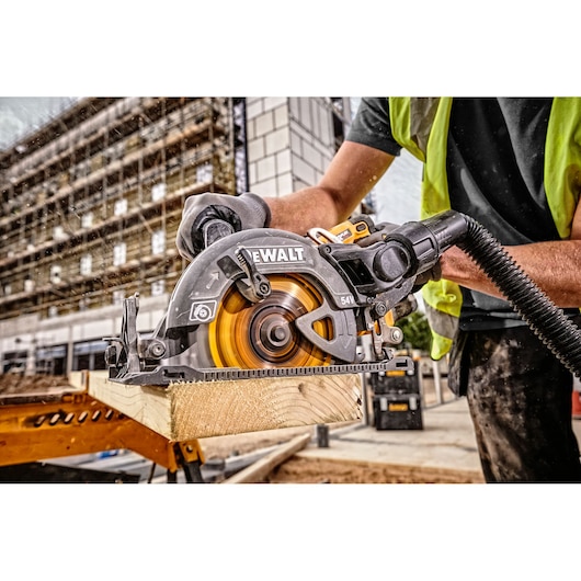 DEWALT circular saw cutting wood on a construction site, operated by a worker in safety gear.