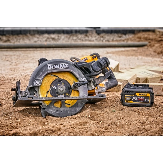 DEWALT circular saw and XR FLEXVOLT battery on a construction site with lumber in the background.