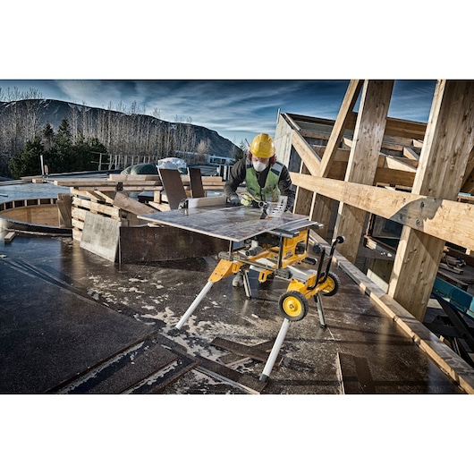 DEWALT DCS7485N table saw in use at a construction site, worker wearing safety gear cutting wood panels.