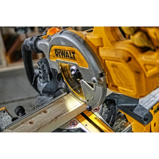 DEWALT miter saw cutting a piece of wood in a workshop. Close-up of the power tool in use.