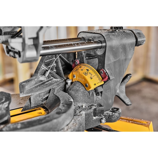 Close-up of a DEWALT miter saw angle gauge, showing dust and measurement markings in a workshop setting.