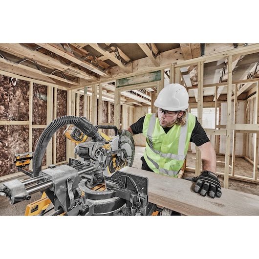 DEWALT DCS781X2-QW, DCS781X2 saw in use on site. Worker in safety gear cutting wood, construction background.