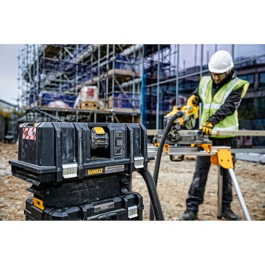 DEWALT vacuum and power tool used at a construction site, worker in safety gear operating equipment outdoors.