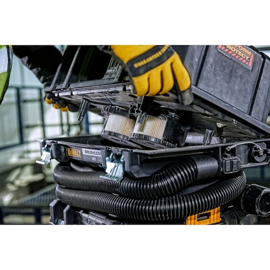 DEWALT DCV586M vacuum with brushless motor and filters being maintained by a gloved hand.