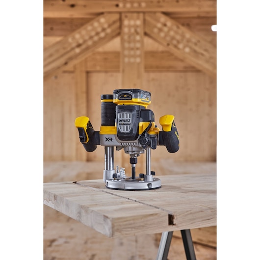 DEWALT cordless router on a wooden table in a workshop, showing yellow and black design and dual handles.