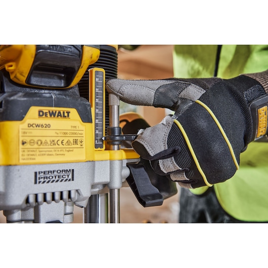 Gloved hand adjusting the DEWALT DCW620 power tool depth gauge during operation.