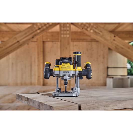 DEWALT router power tool model DCW620NT placed on a wooden work surface in a workshop with timber framing in the background.