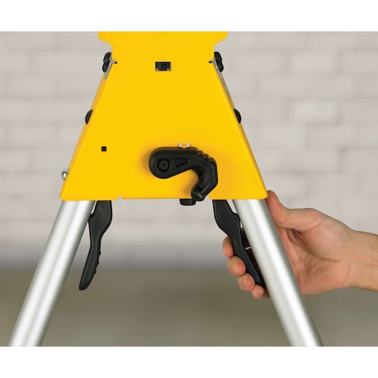 Close-up of a DEWALT work stand adjustment lever being operated by hand, showing its yellow and metal frame.