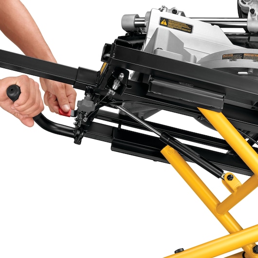 Close-up of DEWALT DE7260 stand with yellow legs, showing adjustment handle being operated by a person.