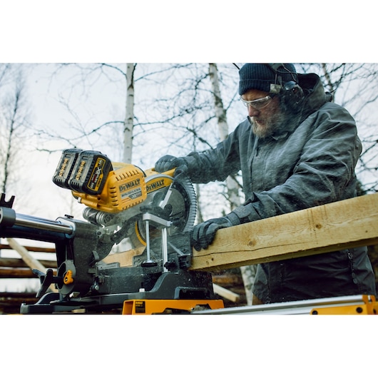 Person cutting wood outdoors with a DEWALT DHS780T2A cordless saw.