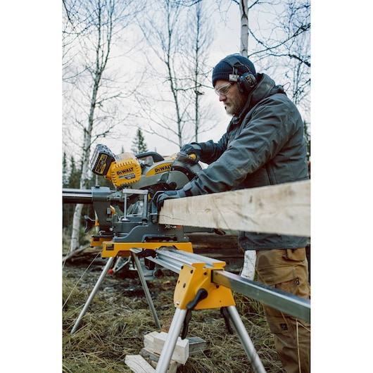 Person using a DEWALT DHS780T2A saw outdoors to cut wood. Face is blurred for privacy.