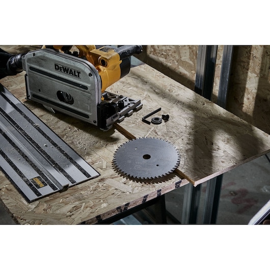 DEWALT saw with a blade and accessories on a wooden workbench in a workshop setting.