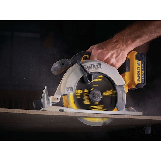 DEWALT cordless circular saw in use, cutting through a wooden board close-up.