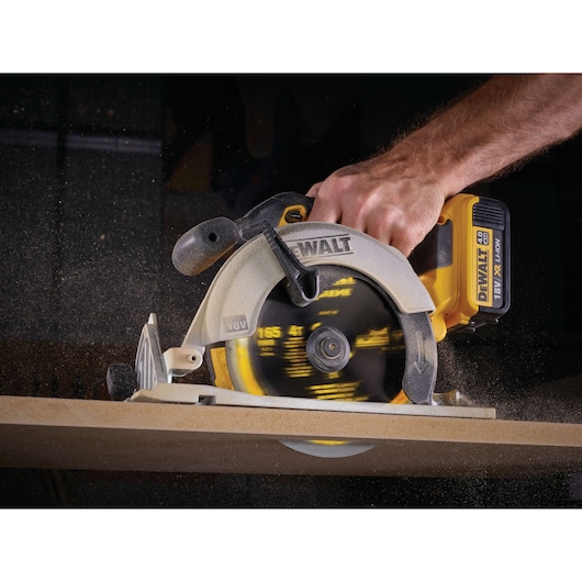DEWALT cordless circular saw cutting wood, close-up of hand and spinning blade in action.