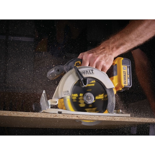 DEWALT cordless circular saw cutting wood with visible sawdust flying.
