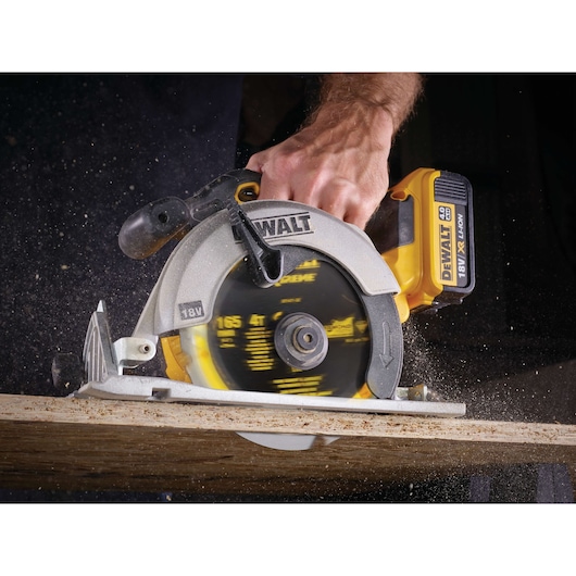 DEWALT 18V cordless circular saw cutting wood, held by a hand with sawdust flying during operation.
