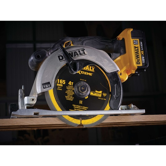 DEWALT DT1471 18V cordless circular saw cutting wood, close-up of blade and battery.